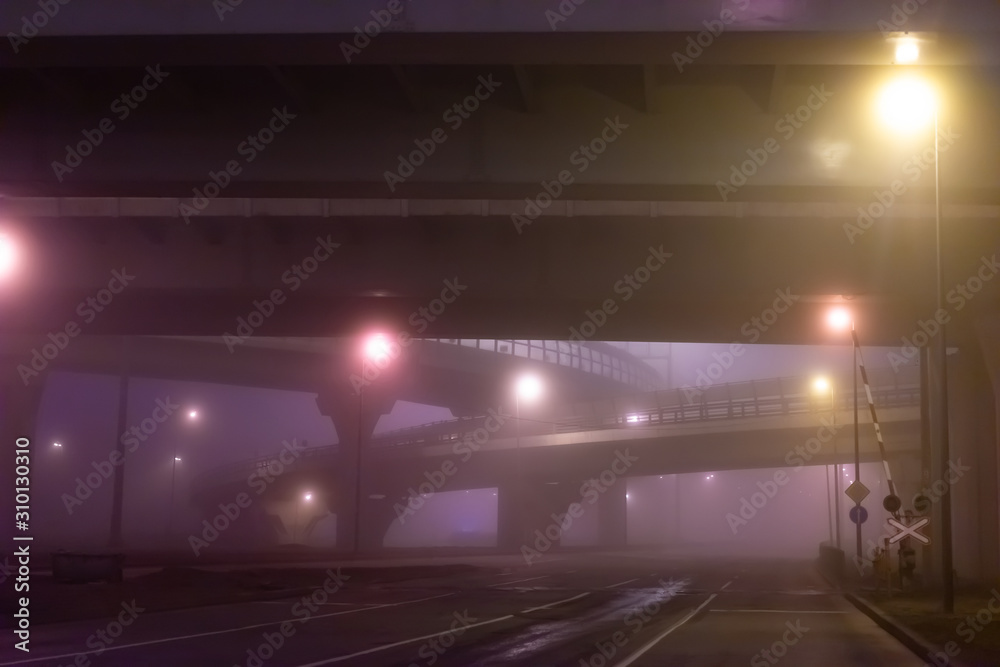 Transport concept. Car interchange in the fog. Railway crossing. Rail and road on a cloudy evening. Highways in the fog. Deserted highways and crossings. Transport concept. Car interchange in the fog. Railway crossing. Rail and road on a cloudy evening. Highways in the fog. Deserted highways and crossings.