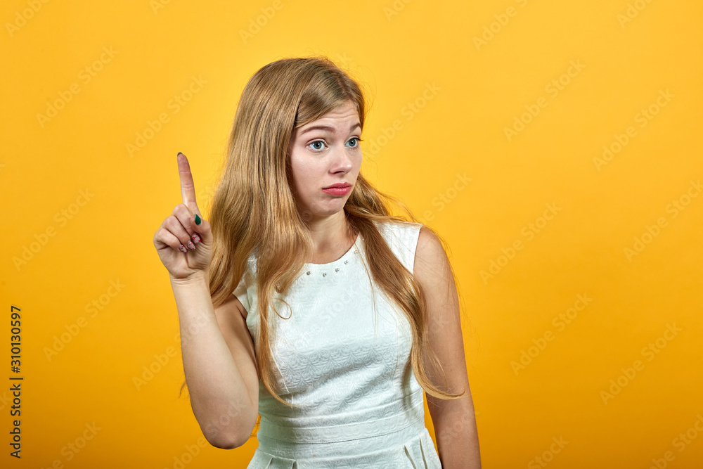 Shocked young woman having idea, pointing up, looking disappointed over isolated orange background in white shirt. Lifestyle concept Shocked young woman having idea, pointing up, looking disappointed over isolated orange background in white shirt. Lifestyle concept