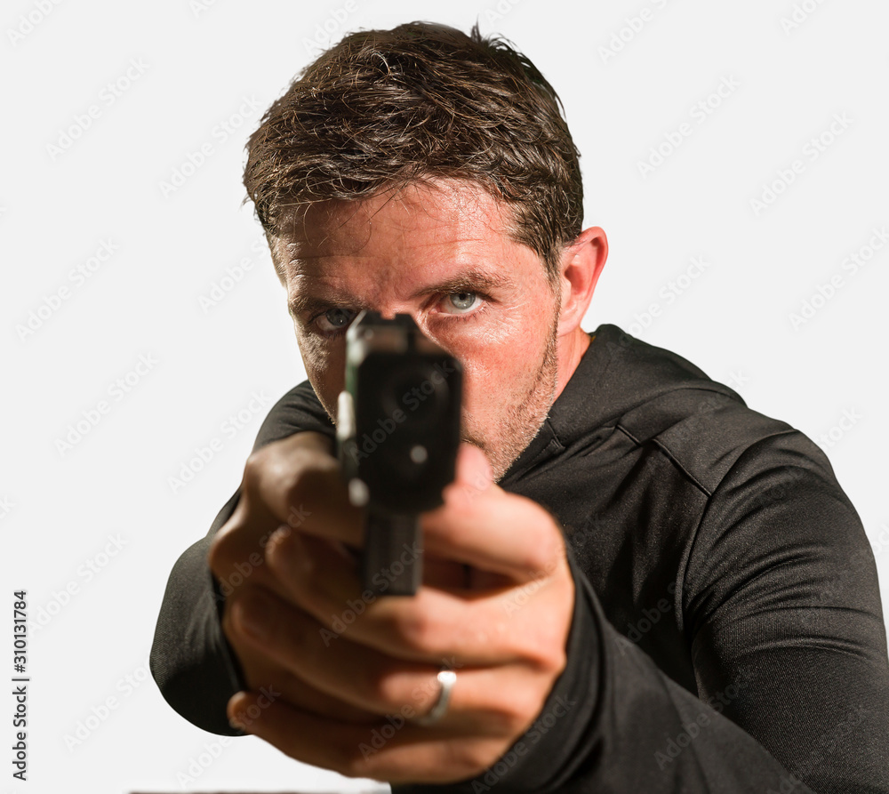 action portrait of serious and attractive hitman or special agent man holding gun pointing the handgun to the camera in Hollywood style movie isolated on studio background action portrait of serious and attractive hitman or special agent man holding gun pointing the handgun to the camera in Hollywood style movie isolated on studio background