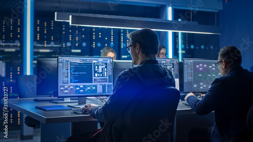 Team of IT Programers Working on Desktop Computers in Data Center Control Room. Young Professionals Writing on Sophisticated Programming Code Language photo