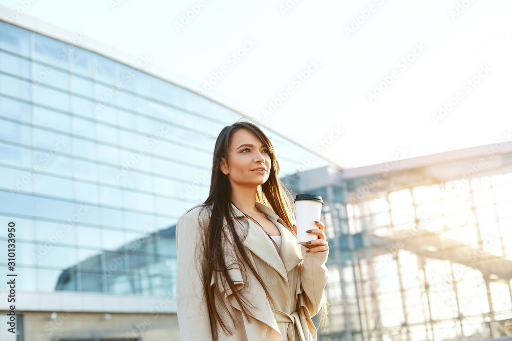 Business woman holding cup of coffee near office. Portrait of beautiful smiling female,standing outdoors.