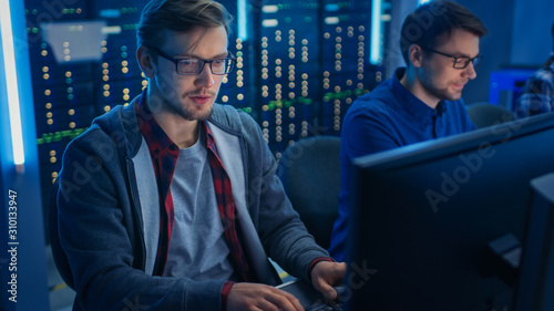 Team of Young IT Programers Working on Desktop Computers in Data Center System Control Room. Displays Show Concept: Software Development / Code Writing / Database Architecture. Technical Department