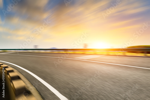Blurred moving asphalt road and colorful sky at sunset