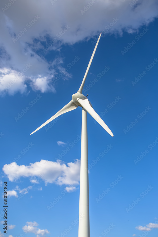 View of a wind turbine on top of mountains, cloudy sky as background View of a wind turbine on top of mountains, cloudy sky as background