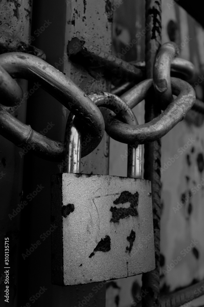 Chain and rusty lock on front metal door. Black and white pictures Chain and rusty lock on front metal door. Black and white pictures