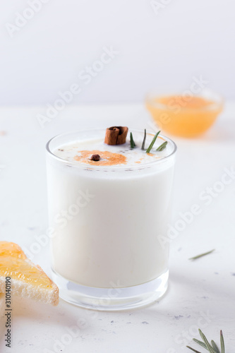 Lassi milk drink on a white plate next to orange jam and sandwiches.