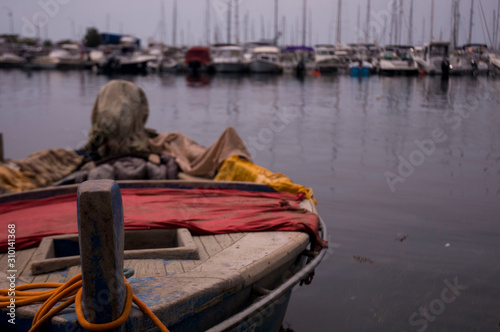 Wooden boat with red and yellow colors. Against the background of yachts on a cloudy day.