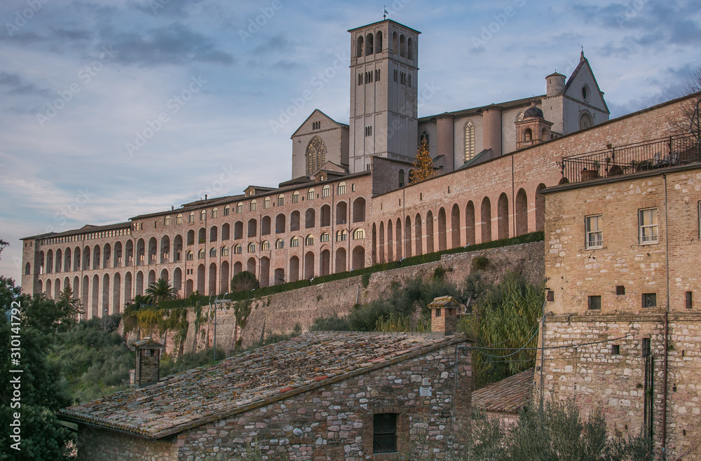Assisi, Umbria, Italy - Panoramic view of Basilica of Saint Francis of Assisi with christmas tree at dusk