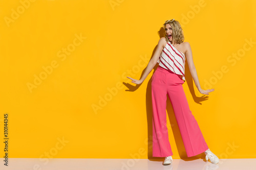 Stylish Young Woman In Pink Wide Leg Trousers Is Standing In The Sunlight And Shouting