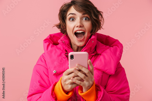 Portrait of young surprised woman using cellphone and screaming