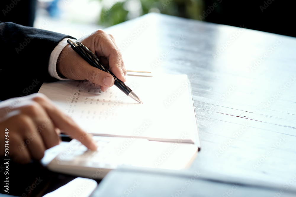 Businessman analyzing investment charts and pressing calculator buttons over documents. Accounting Concept. Businessman analyzing investment charts and pressing calculator buttons over documents. Accounting Concept.