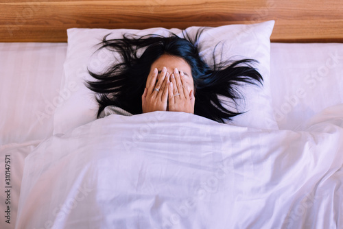 Nightmare or bad dream,Asian woman with scared and panic while lying down under the blanket in bedroom photo