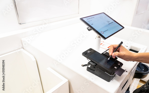 customer signing the signature for paying bill. customer uses a credit card to pay for goods by the machine automatically in the shop, new normal payment concept.