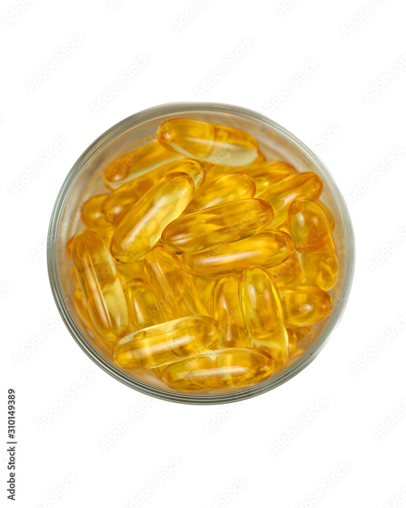 Yellow translucent pills in a glass Cup on a white background. Isolate. Omega, vitamins, food supplements.