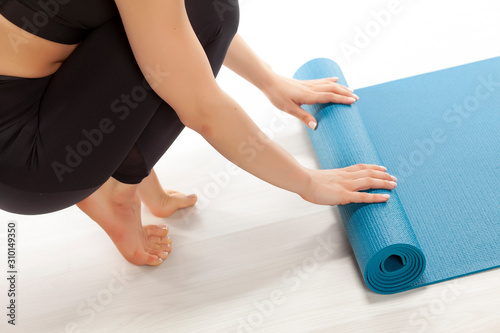 Young yoga woman rolling her yoga mat.