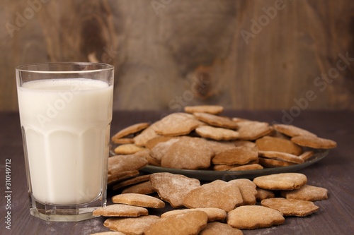 Transparent glass cup with milk and ginger spicy cookies on a wooden table