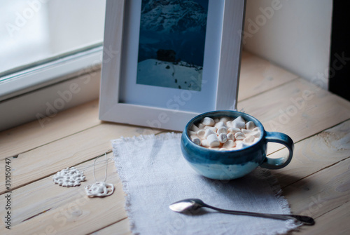 A cup of cacao with marshmellows and christmas decoration on the table with colorful background. Chistmas holiday background. Phantom Blue.