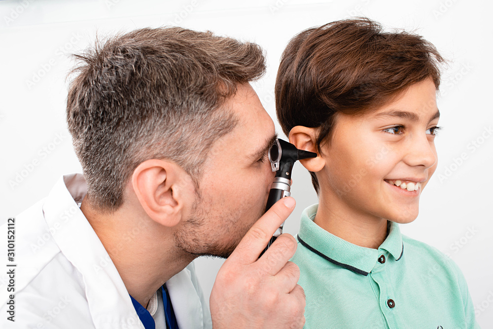 Pediatrician examining little mixed race child with otoscope, hearing exam of child Pediatrician examining little mixed race child with otoscope, hearing exam of child
