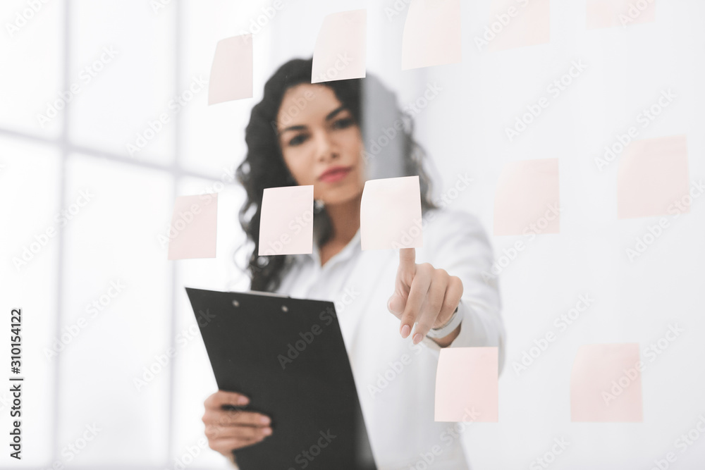 Hispanic businesswoman making notes on glass wall Hispanic businesswoman making notes on glass wall