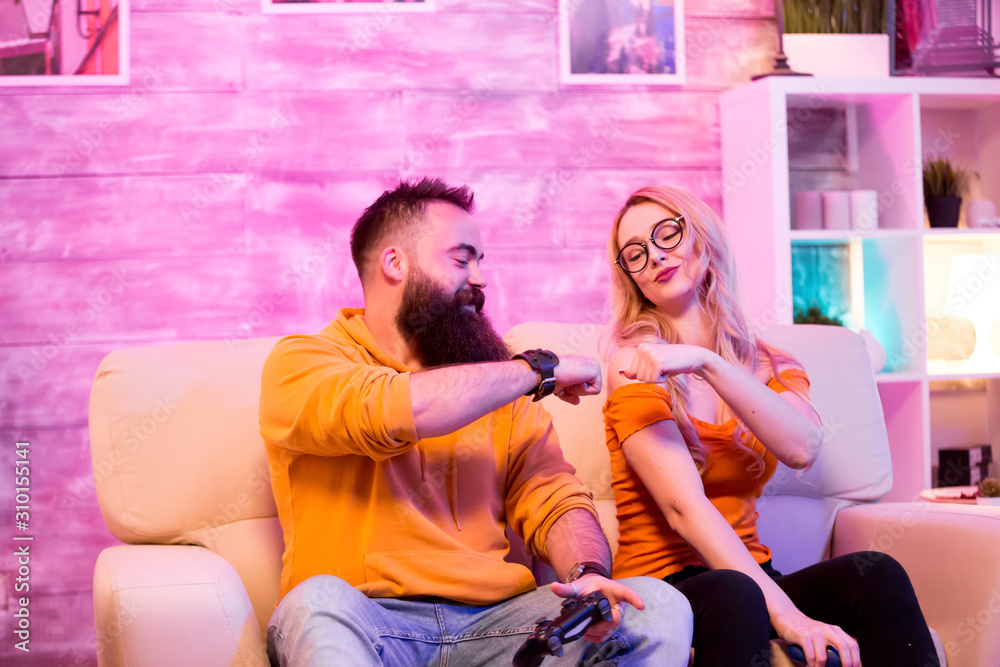 Naklejka premium Young couple giving fist bump after playing online games