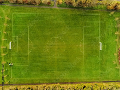 Aerial view, soccer or football field under maintenance, Traktor with feeder and trail all over the pitch.