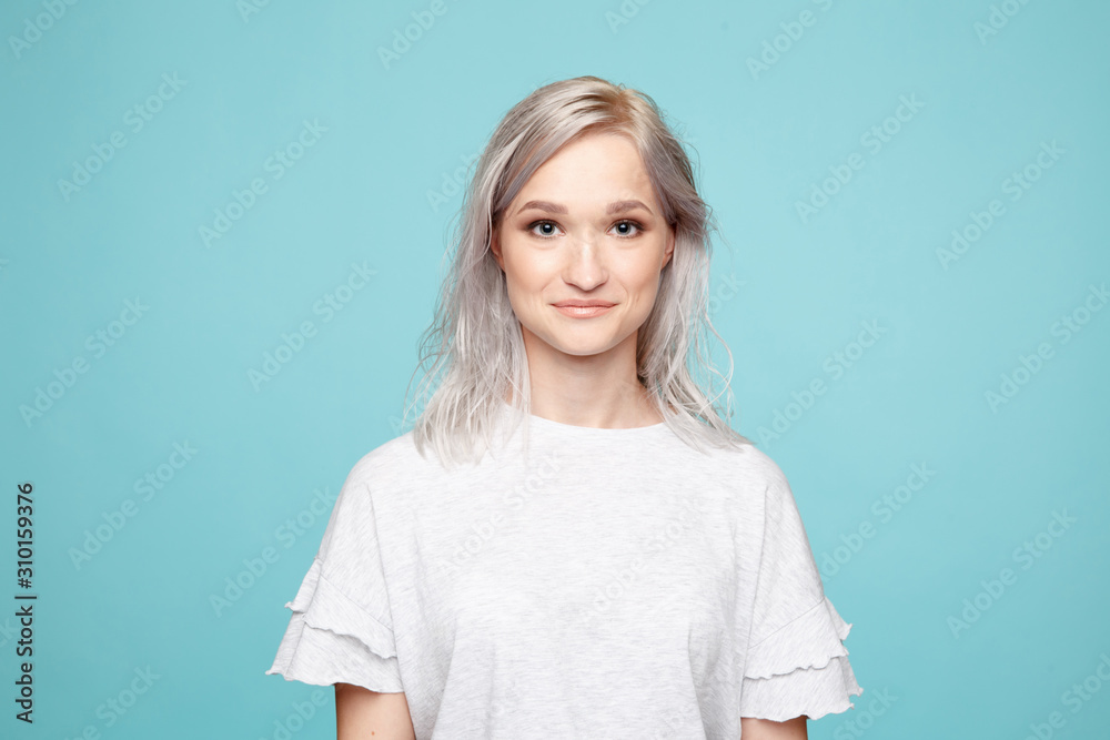 Portrait of young female in the white t-shurt in the blue background Portrait of young female in the white t-shurt in the blue background