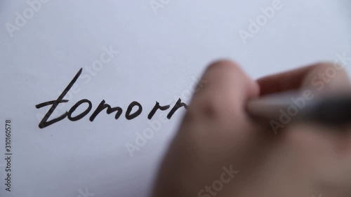 Hand writing Tomorrow on white paper