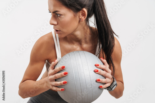 Image of young woman in sportswear holding fitness ball during workout