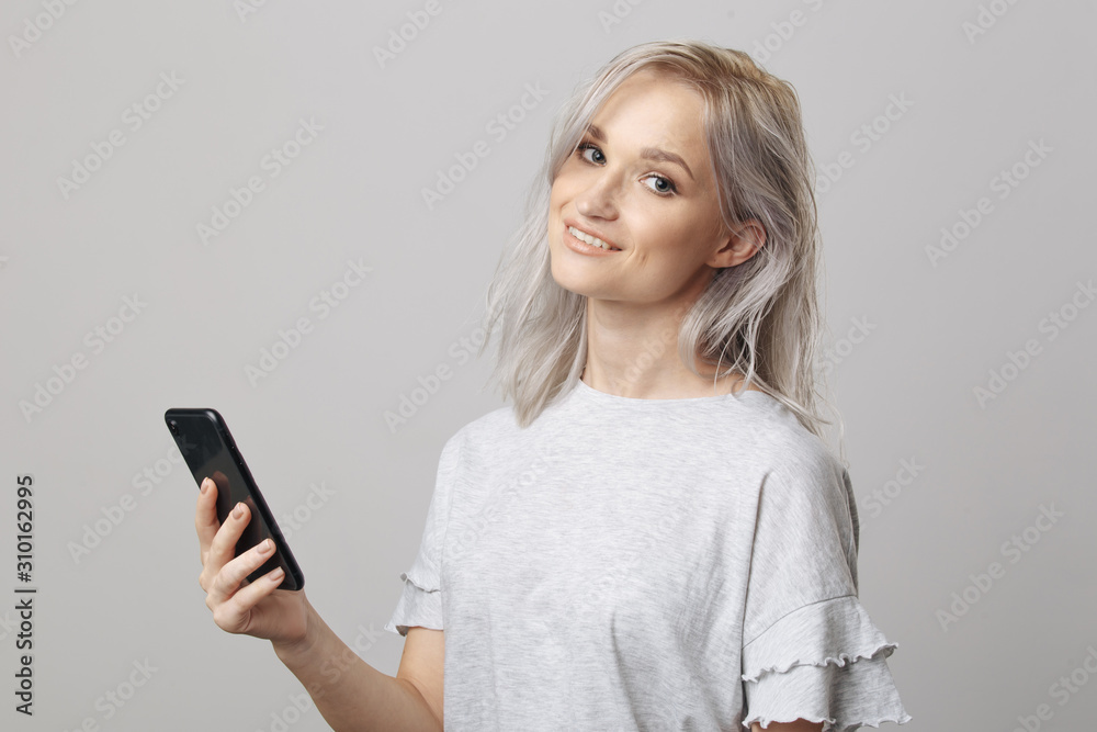Naklejka premium Happy blond woman in studio holding phone