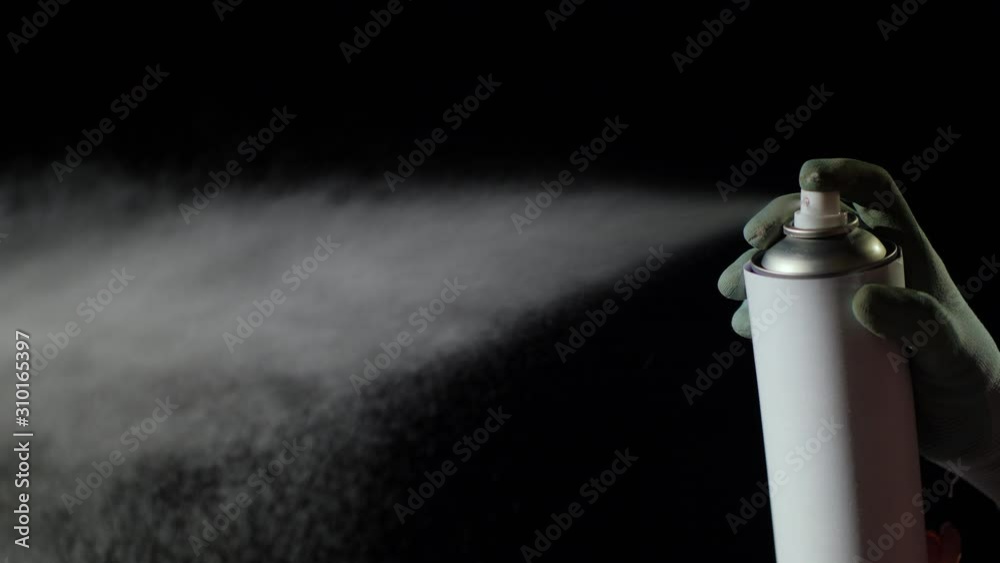 Hand in a pen sprays spray on a black background