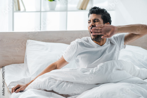 handsome bi-racial man yawning and waking up in morning