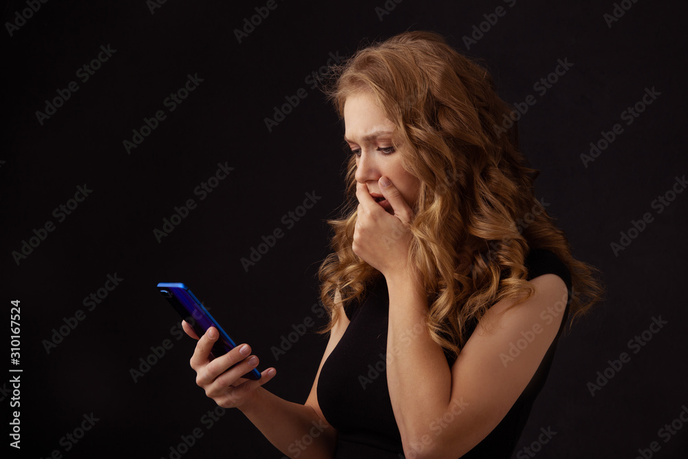 Obraz premium Scared annoyed girl watching phone and closing her mouth