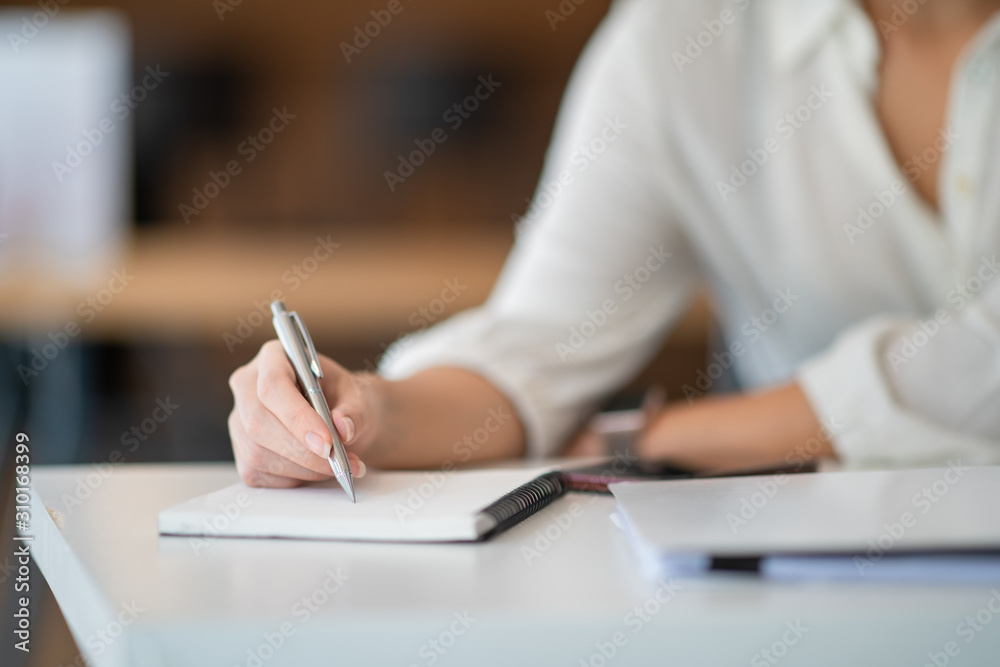 female hands with pen writing on notebook female hands with pen writing on notebook