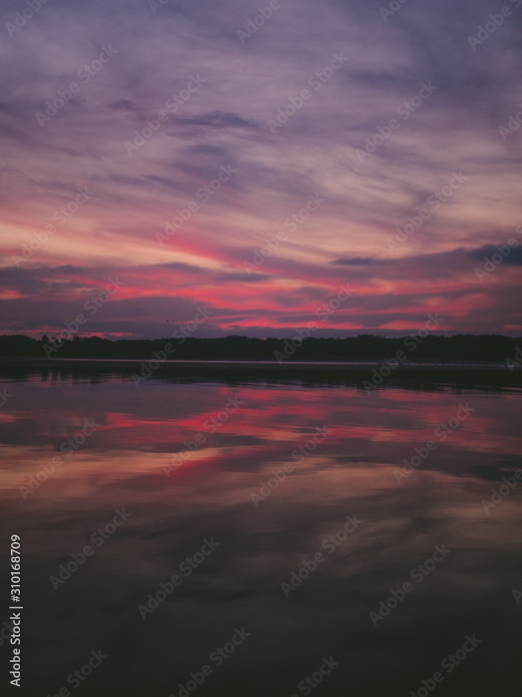 Vertical shot of the cloudy sky during the sunset reflected in the water