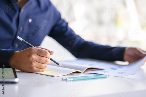 Wallpaper Mural Close up of male hand writing with pencil on the book. Businessman working with data information in the office. Torontodigital.ca