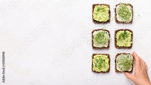 Girl taking vegan toasts with avocado, tofu and microgreens