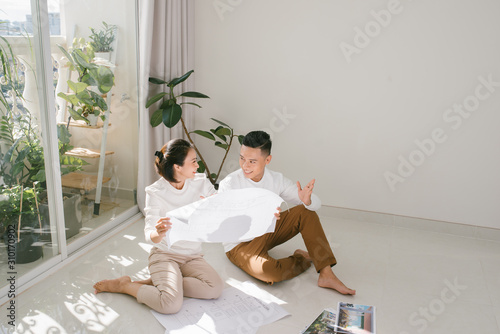 repair, building, renovation and people concept - close up of happy couple looking at blueprint at home