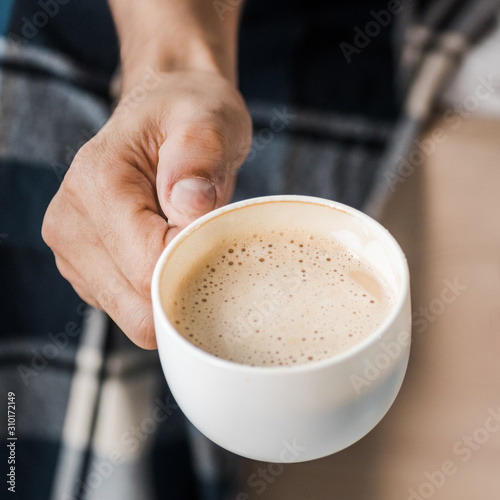 cropped view of bi-racial man holding cup of coffee in morning