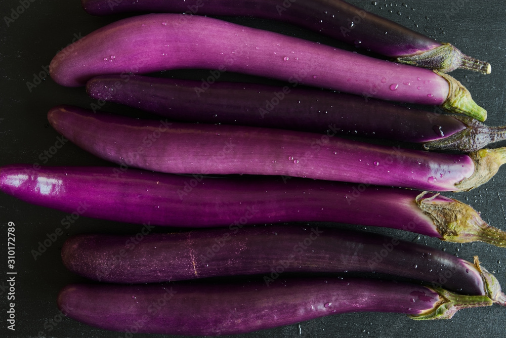 Fresh japanese eggplants on dark background, top view. Fresh japanese eggplants on dark background, top view.