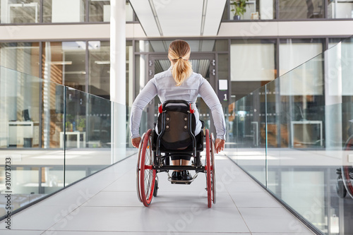 Frau im Rollstuhl im behindertengerechten Bürohaus photo
