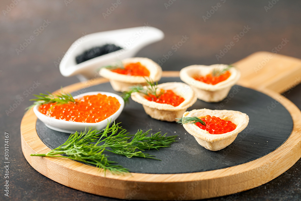 Tartlets with red caviar on a slate board. Valentine's day concept. Selective focus Tartlets with red caviar on a slate board. Valentine's day concept. Selective focus