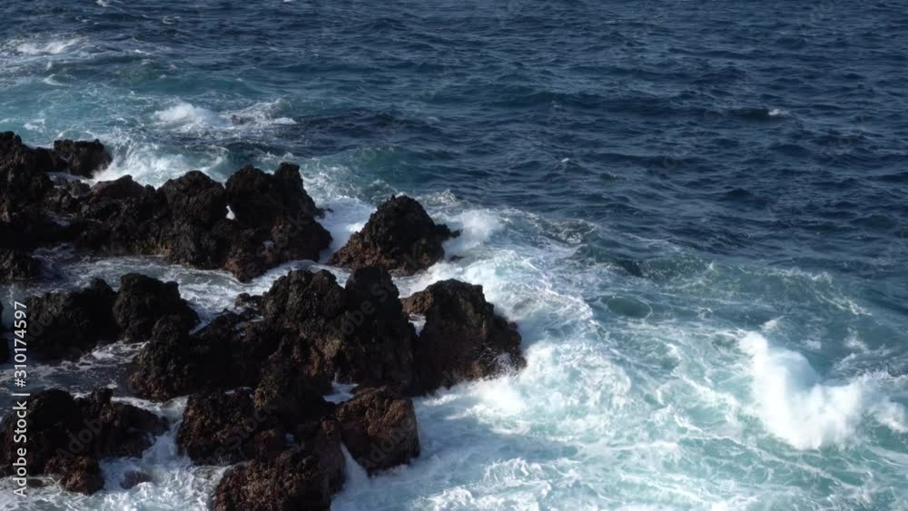 A white crested wave crashes on black lava rocks on Atlantic coast A white crested wave crashes on black lava rocks on Atlantic coast