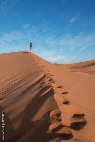 Young girl walking through the dunes in sahara desert in Morocco