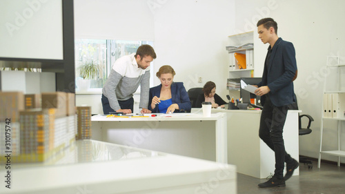 Engineers work with drawings of apartement, colleague put documents on table © iaginzburg