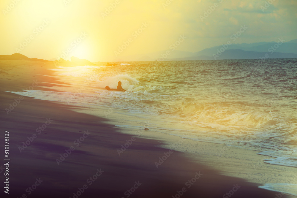 silhouette of happy men in the sea of dark beach at sunset, soft tone like dream