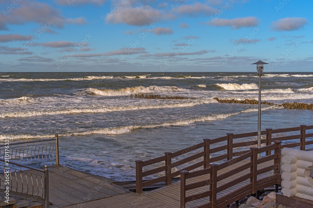 A storm on the Baltic Sea in February. A wooden breakwaters, promenade, lantern