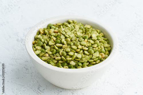 Green peas in white bowl on white background. Dried cereals in cup, vegan food. Side view, close up. photo
