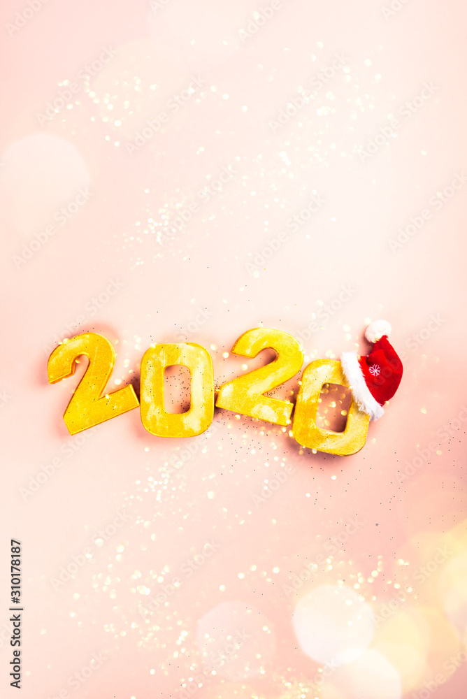 Naklejka premium Happy New Year 2020. Golden digits 2020 with christmas hat are on pink background with glitter. Holiday Party Decoration or postcard concept with top view and copy space.