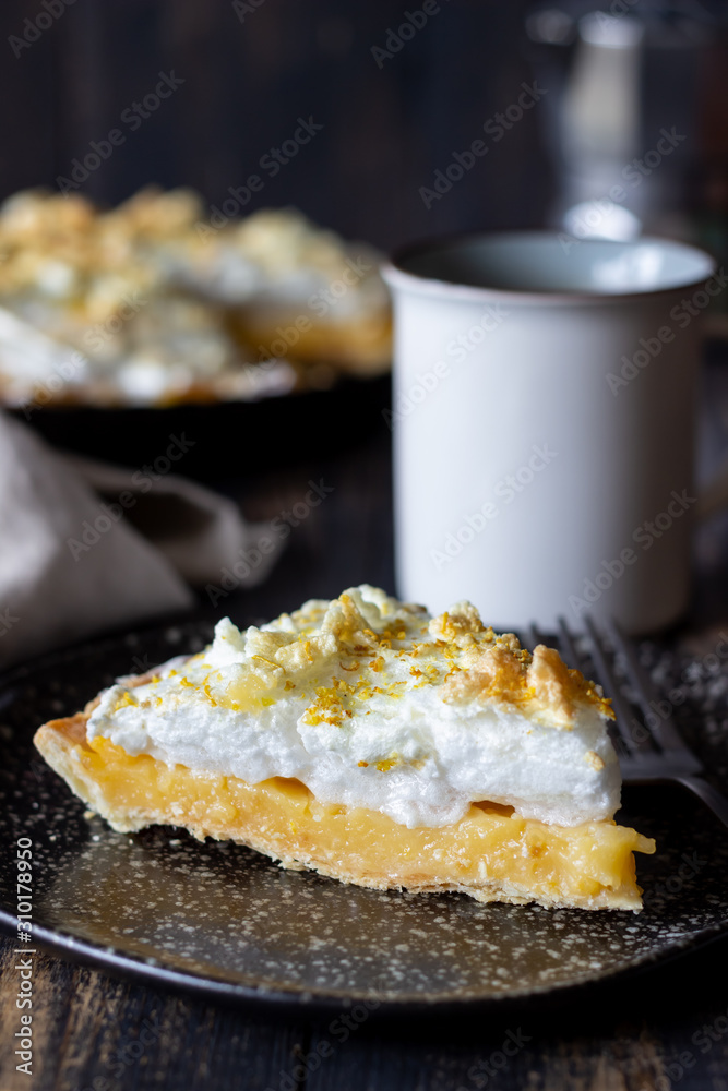 Lemon pie with meringue on a wooden background.