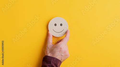 Wooden cut circle with smiling face on it